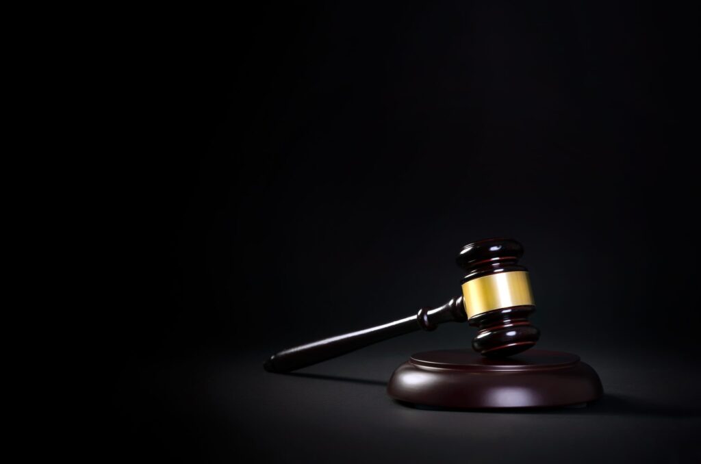 A wooden gavel and block over a dark background representing how one can benefit from calling a Portland criminal defense attorney.