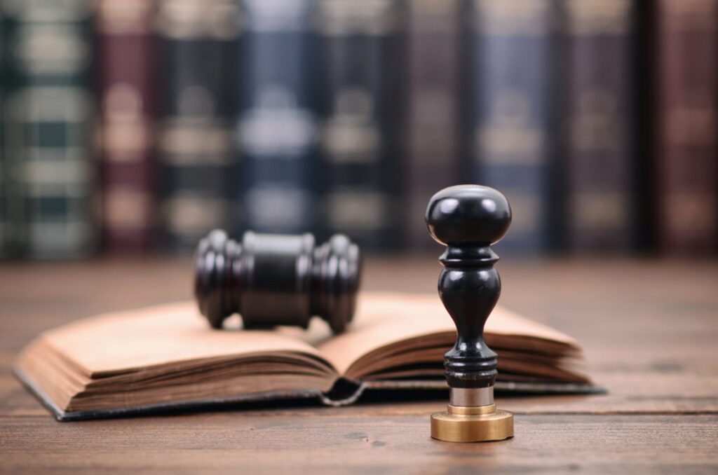 A notary seal, a gavel and books in the background representing how one can benefit from calling a Portland criminal defense attorney.