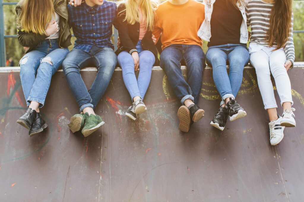 A group of teenagers hanging out, sitting at a ledge. Representing how one can benefit from calling a Portland criminal defense lawyer.