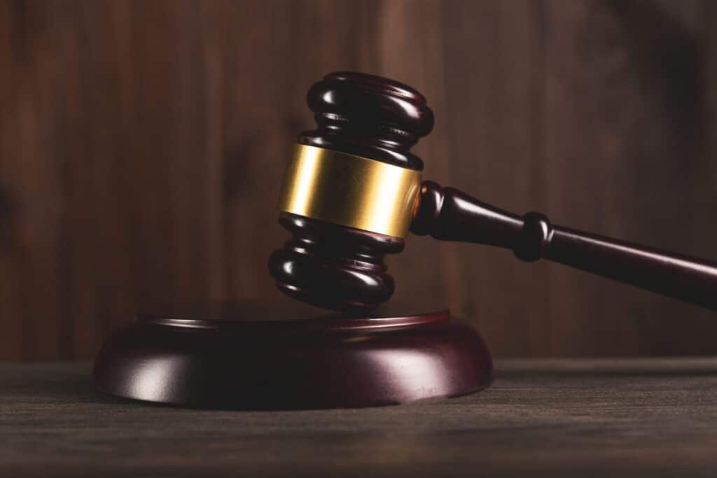 A wooden judge's gavel resting on a wooden block over a brown background. Representing how one can benefit from calling a Portland criminal defense attorney.