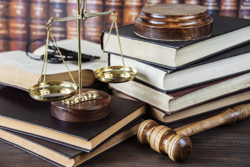 A table with a judge's gavel, a golden balance and several books. Representing how one can benefit from calling a Portland criminal defense attorney.
