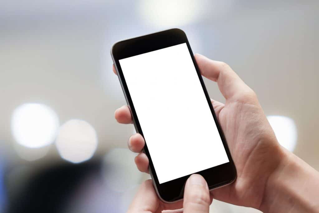 A person holding a smartphone over a blurry background, representing how one can benefit from calling a Portland criminal defense attorney.