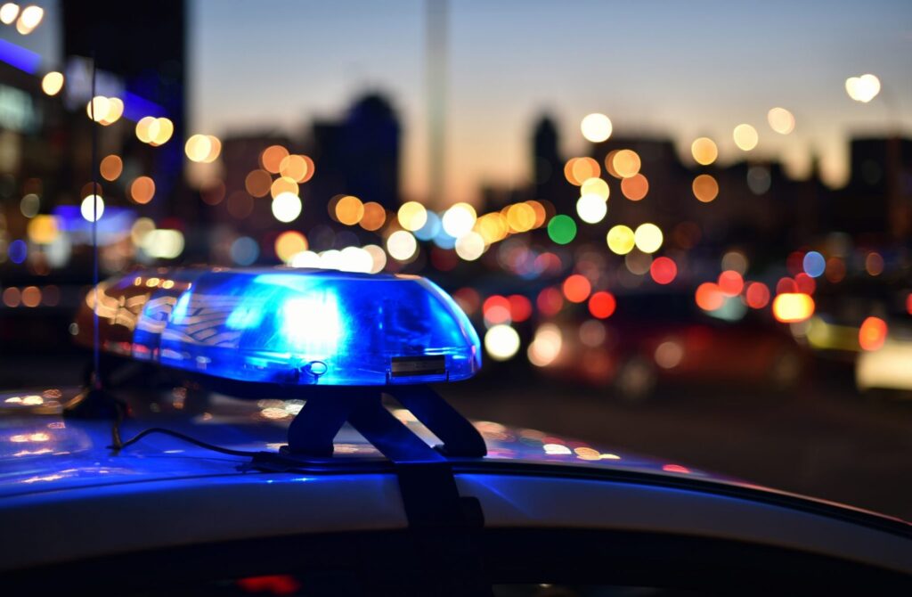 A police car with their lights one in a city at night. Representing how one can benefit from calling a Portland criminal defense attorney.