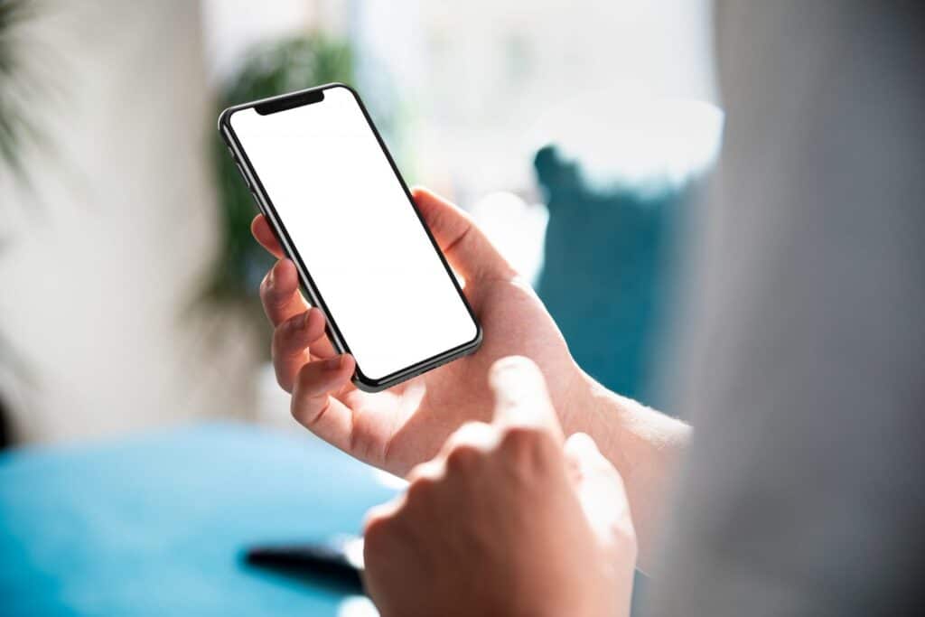 A man holding a smart phone with his right hand. Representing how one can benefit from calling a Portland criminal defense attorney.