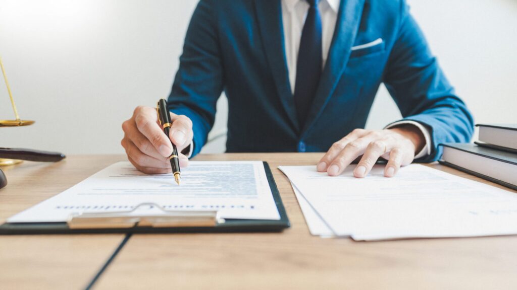 A lawyer doing some paperwork on a desk, representing how one can benefit from calling a Portland criminal defense attorney.