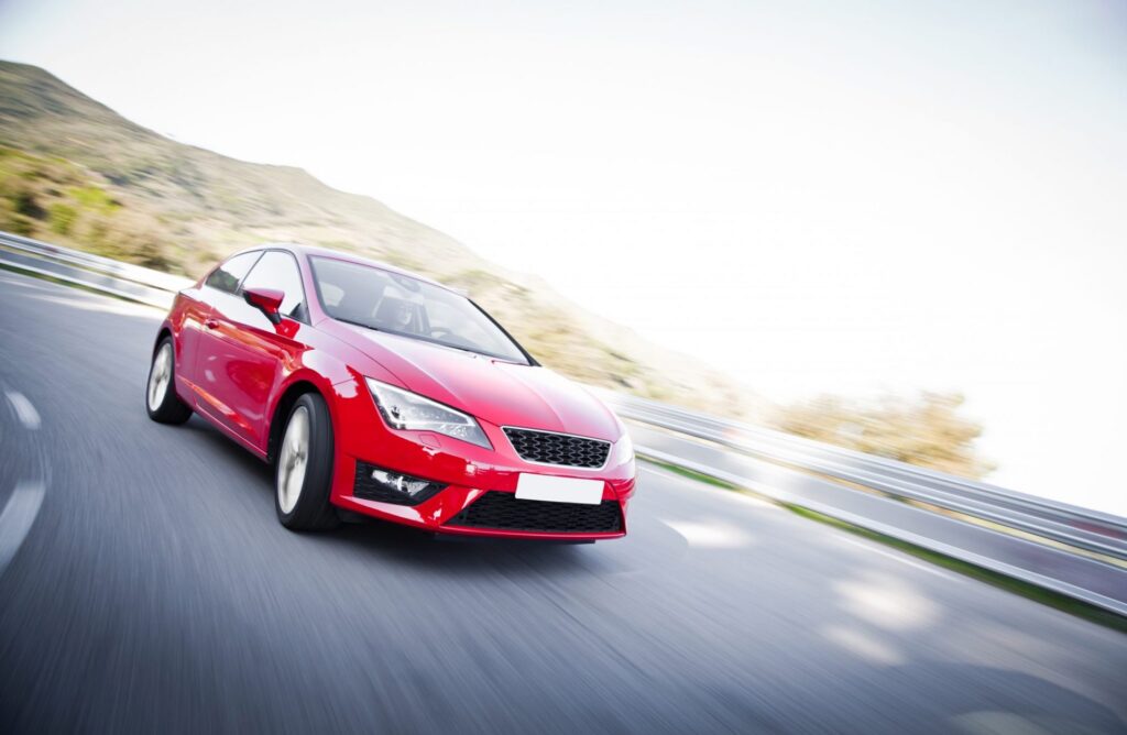 A red car speeding on the road. Representing how one can benefit from calling a Portland criminal defense attorney.