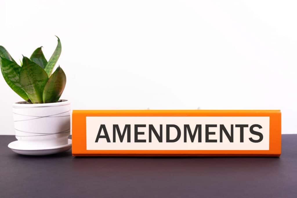 An orange binder labeled "Amendments" next to a plant in a white pot, representing how one can benefit from calling a Portland criminal defense lawyer.