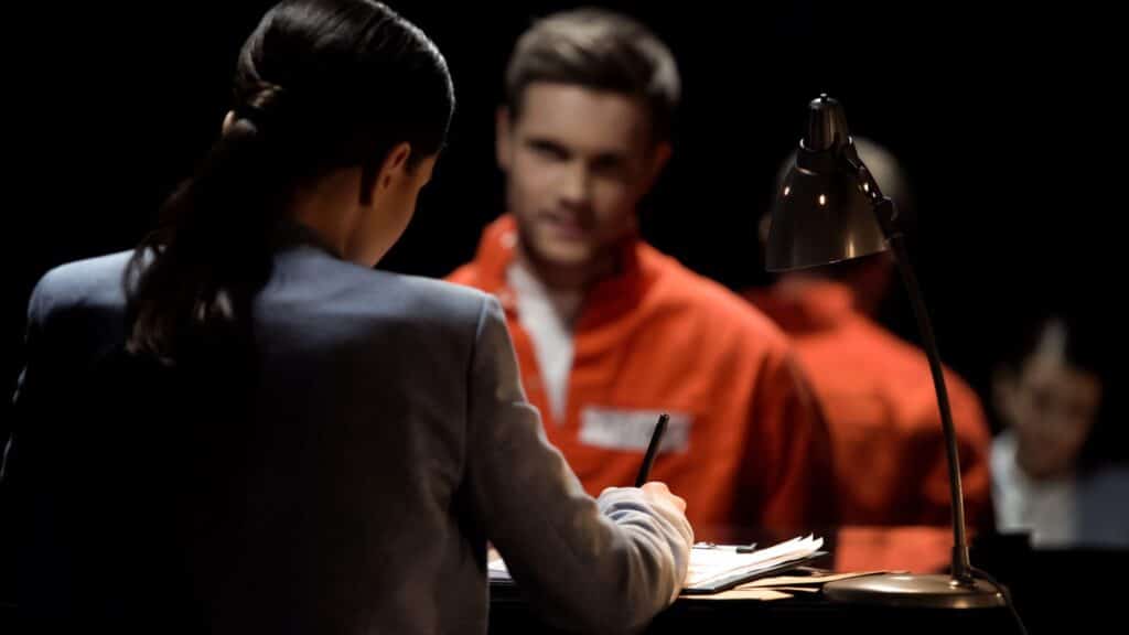A lawyer talking to an inmate wearing an orange jumpsuit, representing how one can benefit from calling a Portland criminal defense attorney.