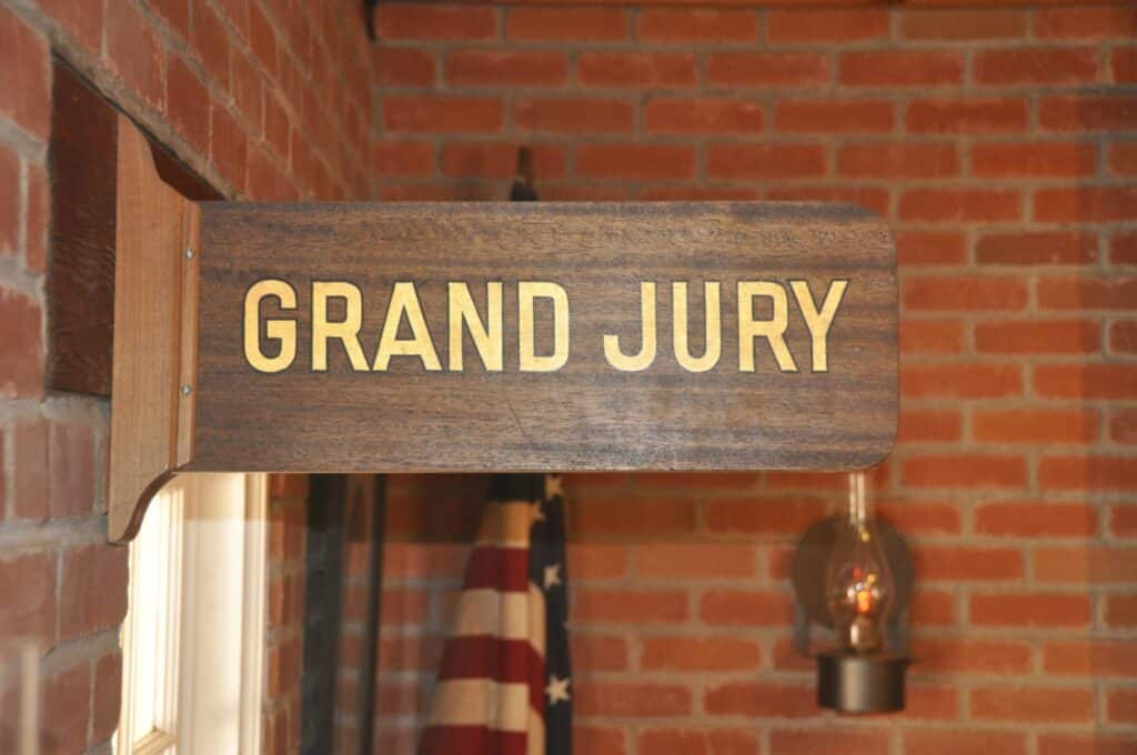 A sign in a room with an American flag that says "Grand Jury", representing how one can benefit from calling a Portland criminal defense attorney.