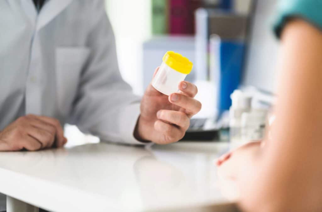 A doctor handing a cup to a patient, representing how one can benefit from calling a Portland criminal defense attorney.