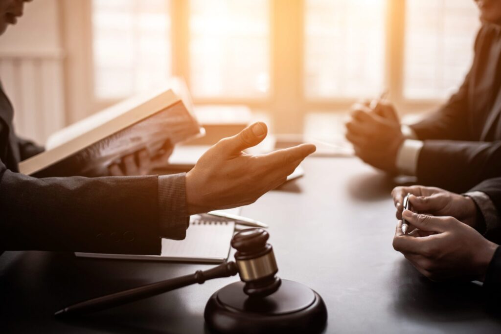 A group of people talking sitting at a table with a judge's gavel, representing how one can benefit from calling a Portland criminal defense attorney.