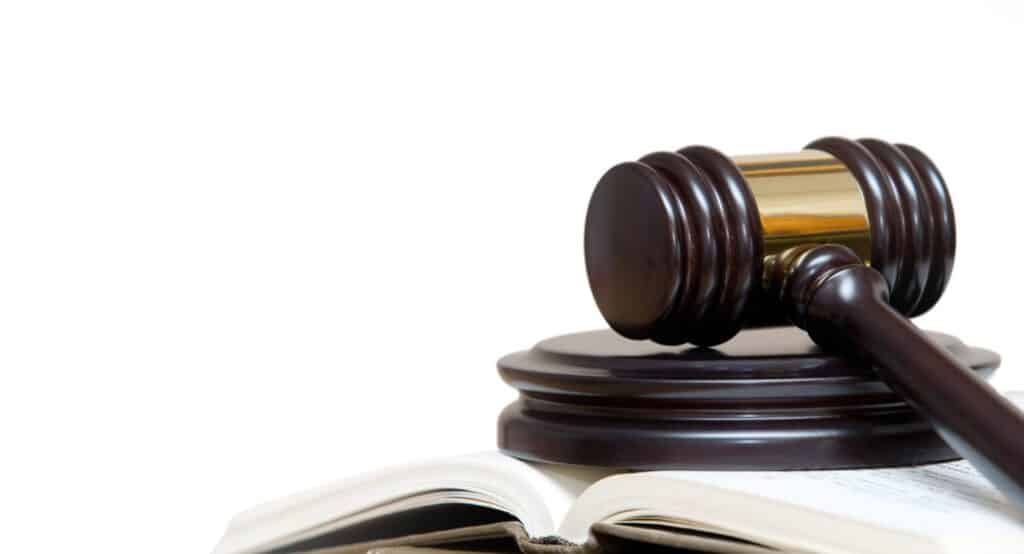 A judge's gavel resting on a block next to a book over a white background. Representing how one can benefit from calling a Portland criminal defense attorney.