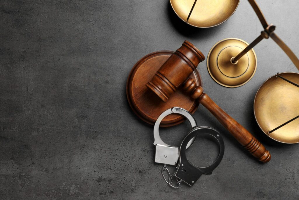 A judge's gavel with a set of handcuffs and a golden scale, representing how one can benefit from calling a Portland criminal defense lawyer.