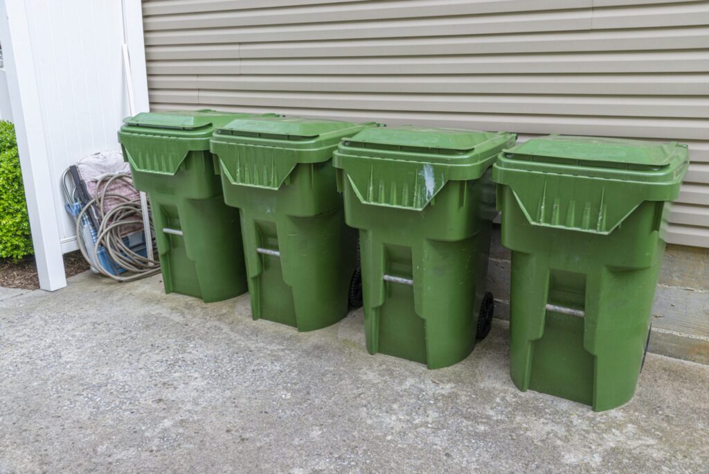 Four large and green trashcans outside of a garage, representing how one can benefit from calling a Portland criminal defense lawyer.