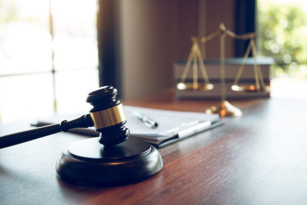 A judge's gavel on a desk with a book and golden balance, representing how one can benefit from calling a Portland criminal defense attorney.