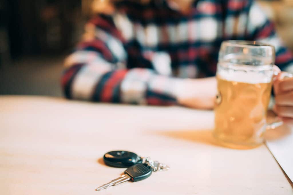 A man drinking a beer and in front of him there are a set of car keys, representing how one can benefit from contacting a Portland criminal defense lawyer.