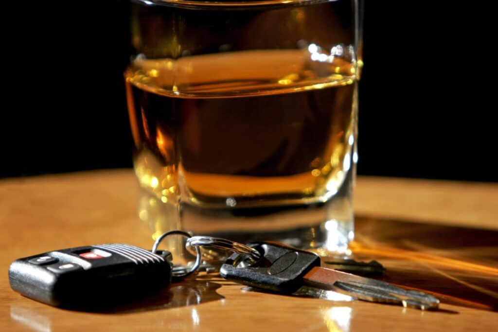 On a table we see a glass with an alcoholic beverage and a set of car keys, representing how one can benefit from contacting a Portland criminal defense attorney.