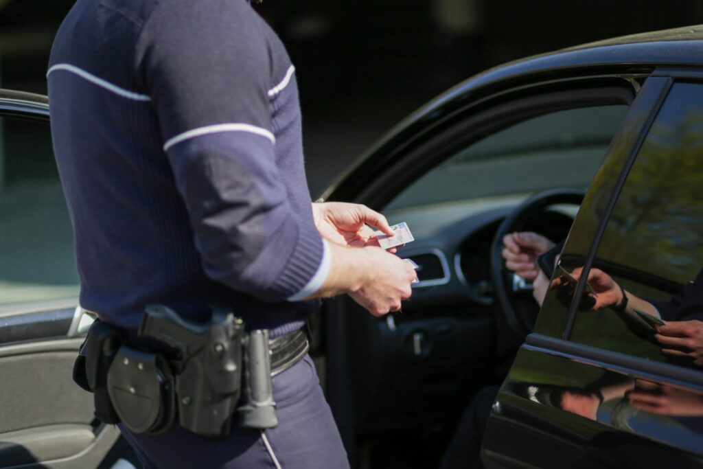 A driver being pullover by a police offer in the street, representing how one can benefit from calling a Portland criminal defense lawyer.