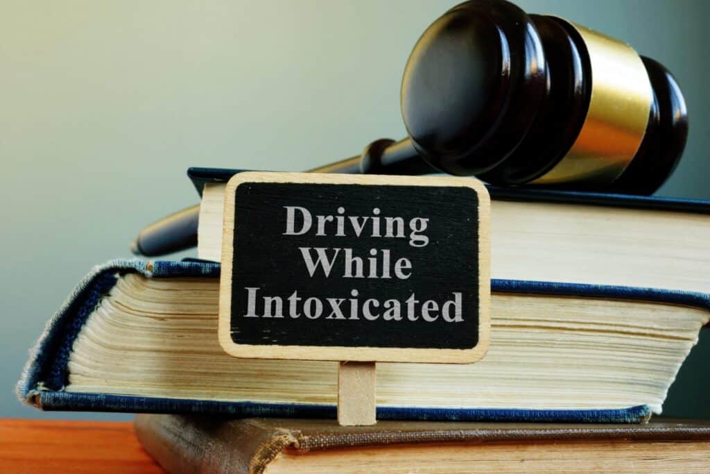 A stack of books with a gavel on the and a sign that says "Driving While Intoxicated", representing how one can benefit from calling a Portland criminal defense lawyer.