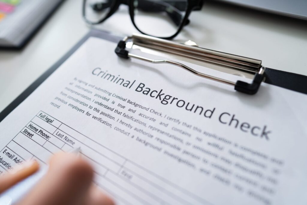 A person filling out a form that says "Criminal Background Check", representing how one can benefit from calling a Portland criminal defense lawyer.