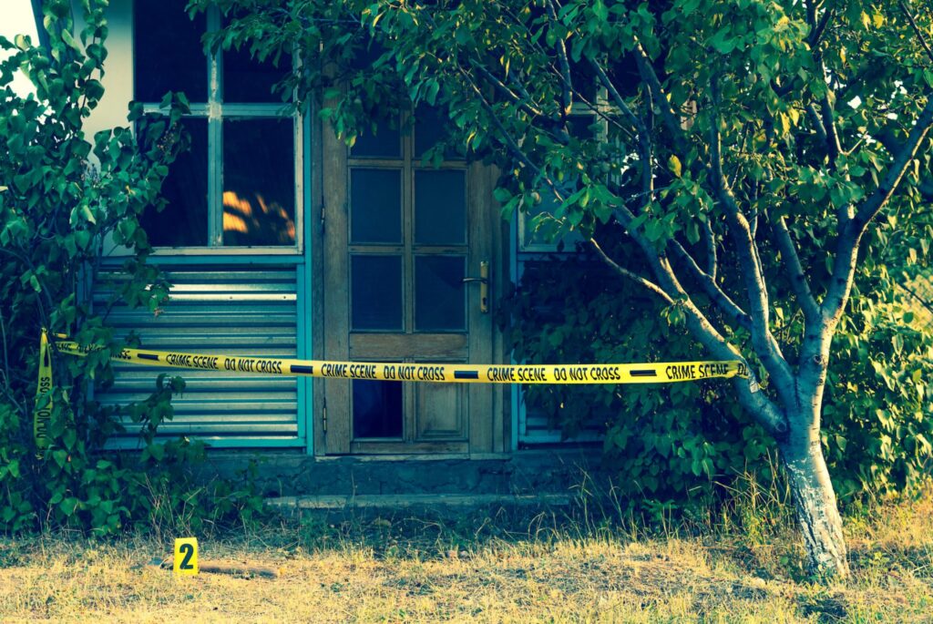 The outside of a house with yellow police tape around it, representing how one can benefit from calling a Portland criminal defense lawyer.