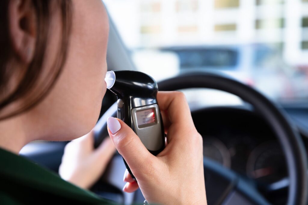 A women using a breathlyzer attach to her car, representing how one can benefit from calling a Portland DUI attorney.