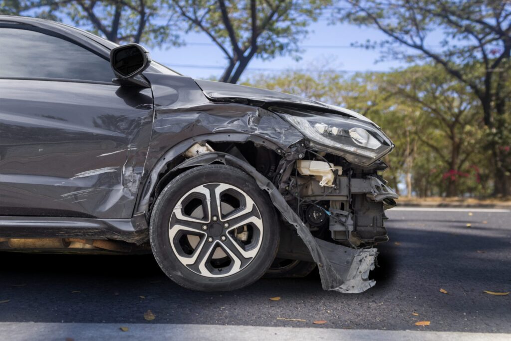 A car in the road with the front bumper destroyed from a collision, representing how one can benefit from calling a Portland criminal defense lawyer.
