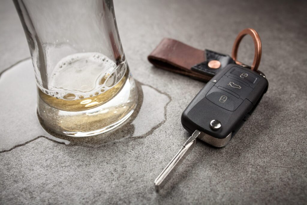 A set if car keys next to a beer glass with some residue, representing how one can benefit from calling a Portland criminal defense lawyer.