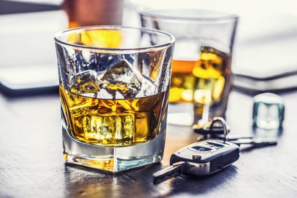 Two glasses with an alcoholic beverage and a set of car keys in between them, representing how one can benefit from calling a Portland criminal defense lawyer.