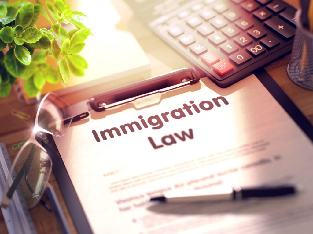 A desk with a pair of glasses, a calculator and a piece of paper that reads "Immigration Law", representing how one can benefit from calling a Portland criminal defense lawyer.
