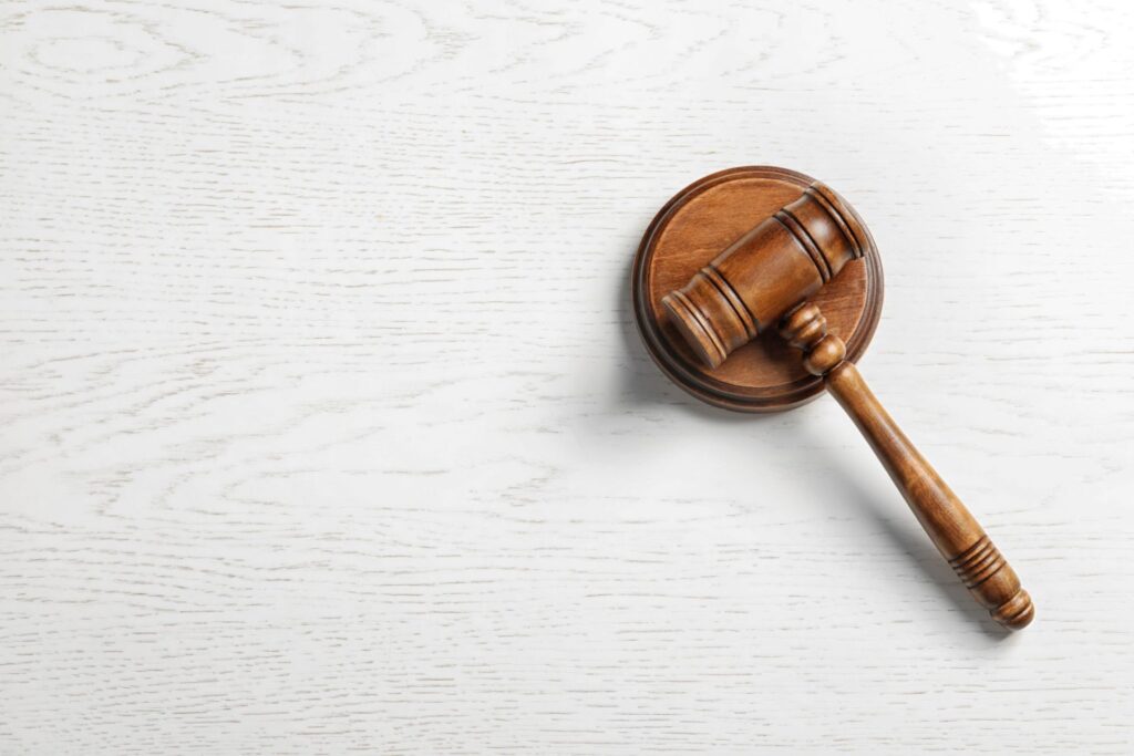 A wooden judge's gavel and block over a light color background, representing how one can benefit from calling a Portland criminal defense lawyer.