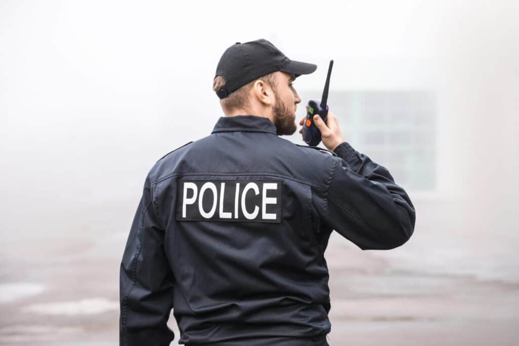 A police officer talking into a radio in a light background, representing how one can benefit from calling a Portland criminal defense lawyer.