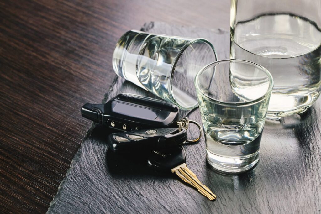Empty shot glasses, a glass of water and a set of car keys, representing how one can benefit from calling a Portland criminal defense lawyer.
