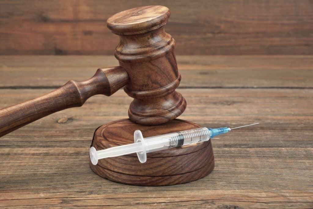 A judge's gavel with a needle with a liquid inside of it, representing how one can benefit from calling a Portland criminal defense lawyer.