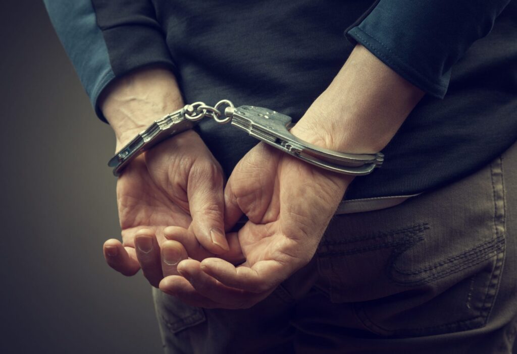 A man with hands behind him in handcuffs, representing how one can benefit from calling a Portland criminal defense lawyer.