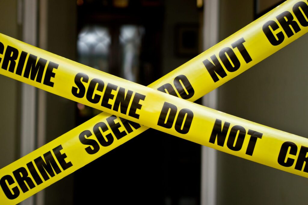 A front door with yellow police tape that say "Crime Scene Do Not Crossed", representing how one can benefit from calling a Portland criminal defense lawyer.