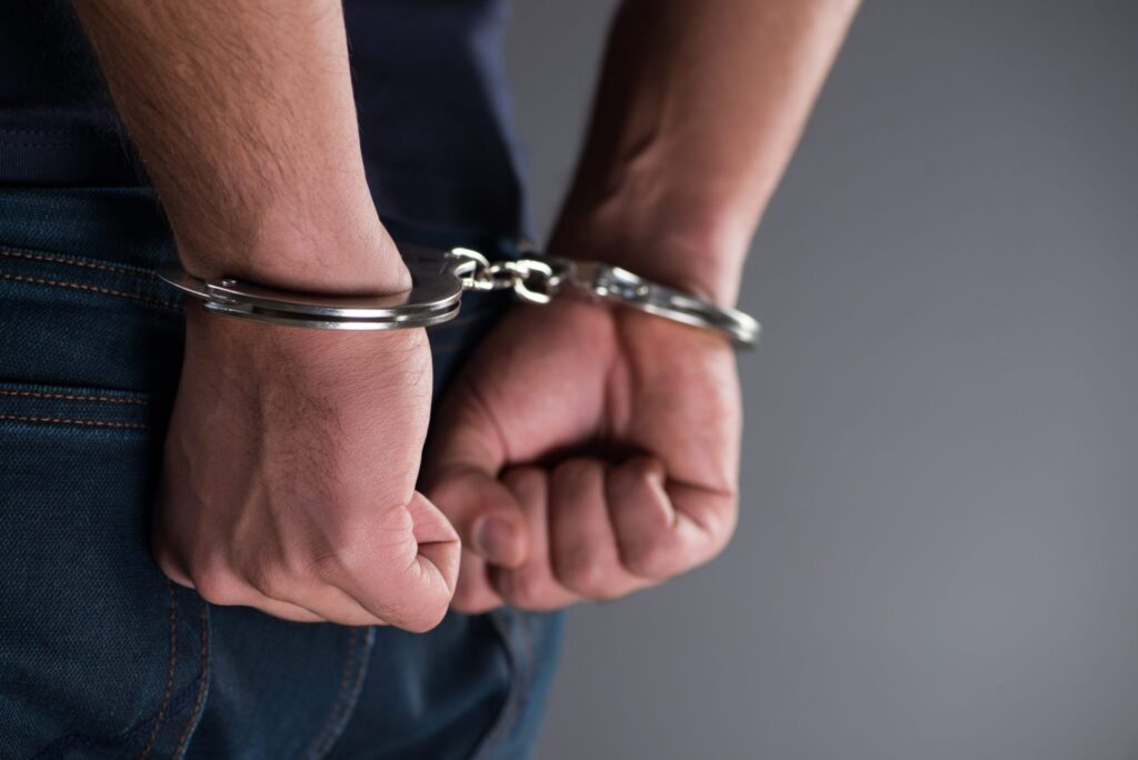 A man with handcuffs with his hands behind him representing how one can benefit from calling a Portland criminal defense lawyer.