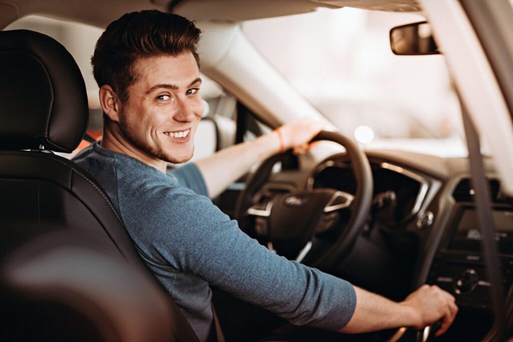 A man driving looking at the back seat with a smile, representing how one can benefit from calling a Portland criminal defense lawyer.