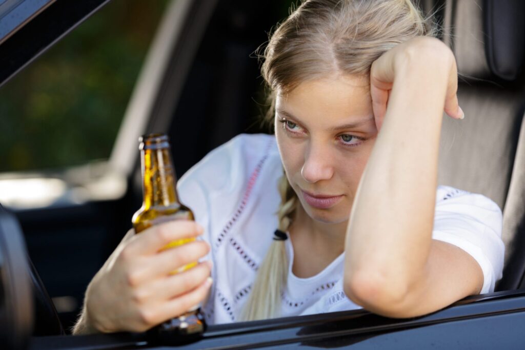 A woman holding a bottle with an alcoholic beverage, she looks like she is under the influence, representing how one can benefit from calling a Portland criminal defense lawyer.