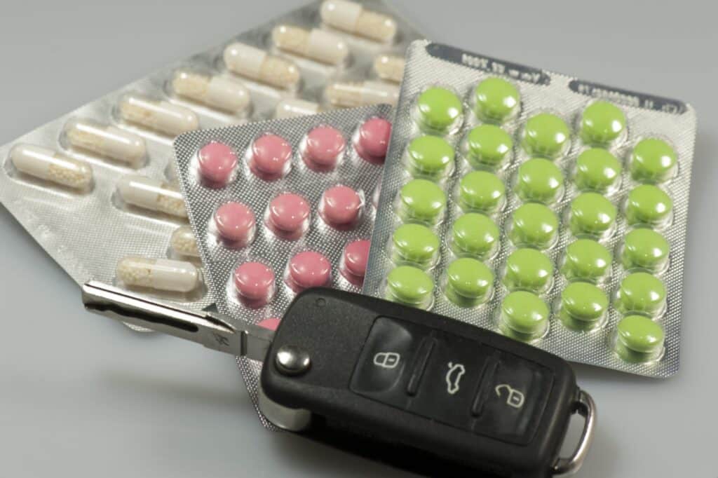 Several different prescription pills with a set of car keys, representing how one can benefit from calling a Portland criminal defense lawyer.