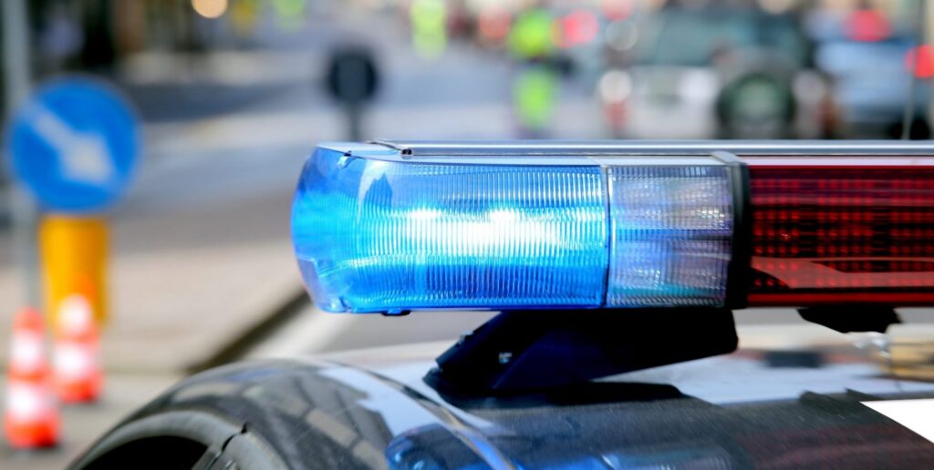 A police car with the lights on during daytime, representing how one can benefit from calling a Portland criminal defense attorney.