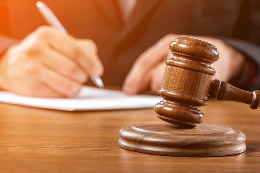 A judge's gavel and a person signing documents in the background, representing how one can benefit from calling a Portland criminal defense lawyer.