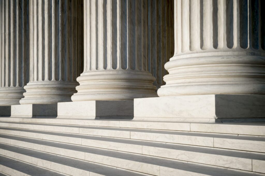 A picture of white pillars in a government building, representing how one can benefit from calling a Portland criminal defense lawyer.