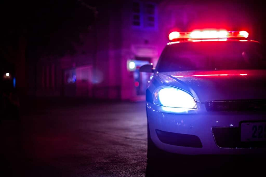 Police car with the lights on at night, representing how one can benefit from calling a Portland criminal defense lawyer.