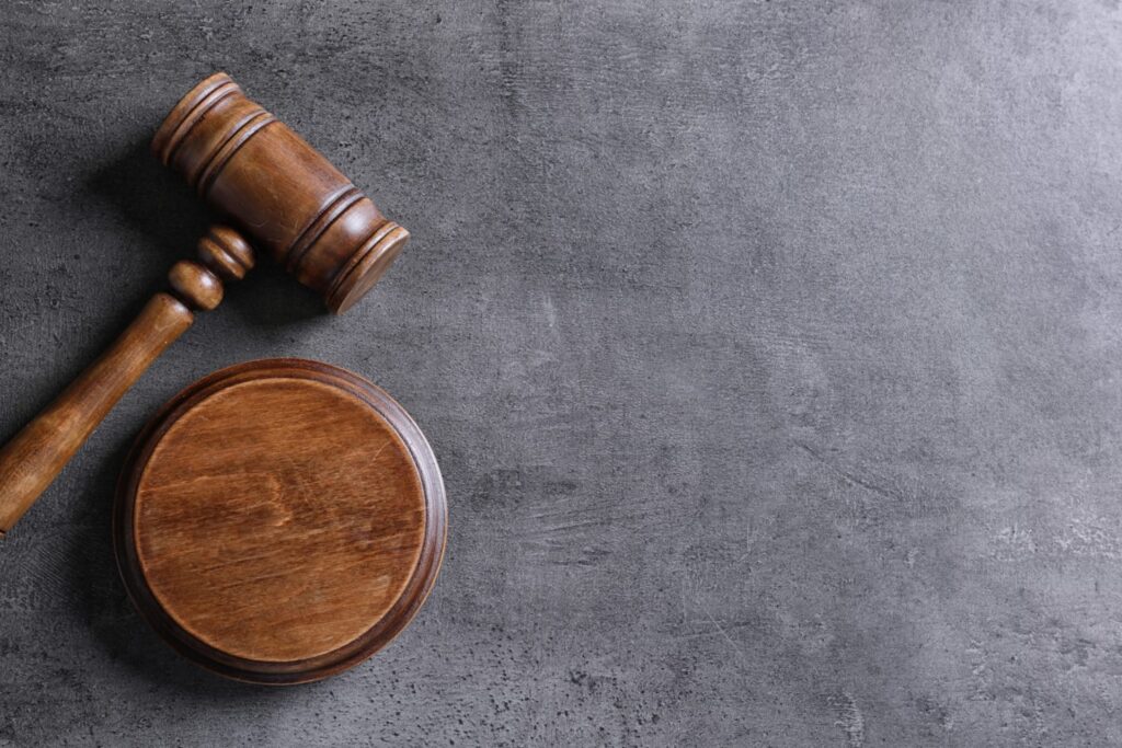 A judge's gavel and block over a gray background, representing how one can benefit from calling a Portland criminal defense lawyer.