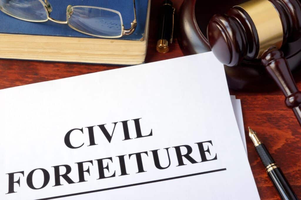 A desk with a book, a gavel, glasses and a paper that says "Civil Forfeiture", representing how one can benefit from calling a Portland criminal defense lawyer.