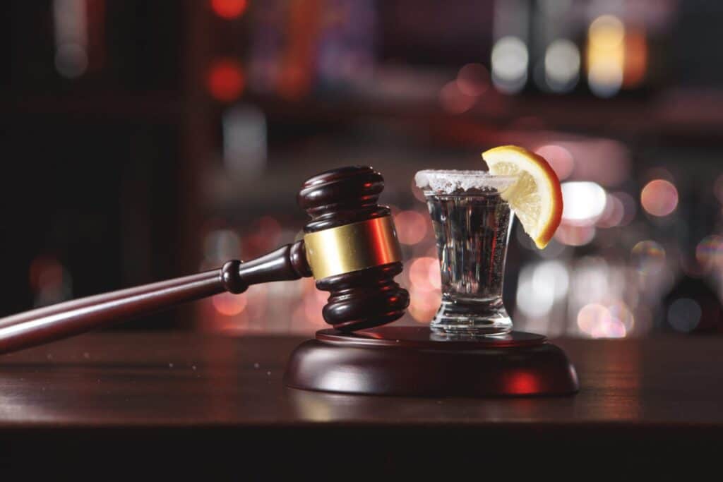 A judge's gavel next to an alcoholic drink serve in a shot glass, representing how one can benefit from calling a Portland criminal defense lawyer.