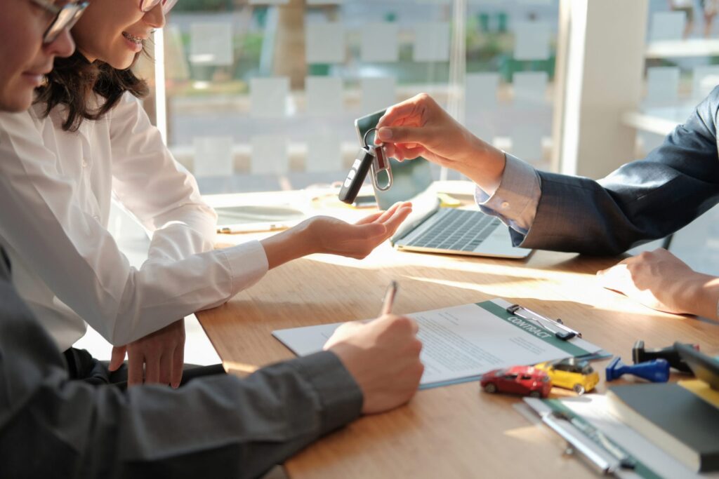 A man working in a rental car place giving the keys to the car to a woman while a another man fills out the paperwork, representing how one can benefit from calling a Portland criminal defense lawyer.