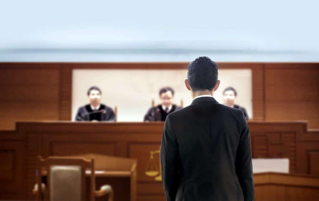A person standing in front of a judge in a courtroom, representing how one can benefit from calling a Portland criminal defense lawyer.
