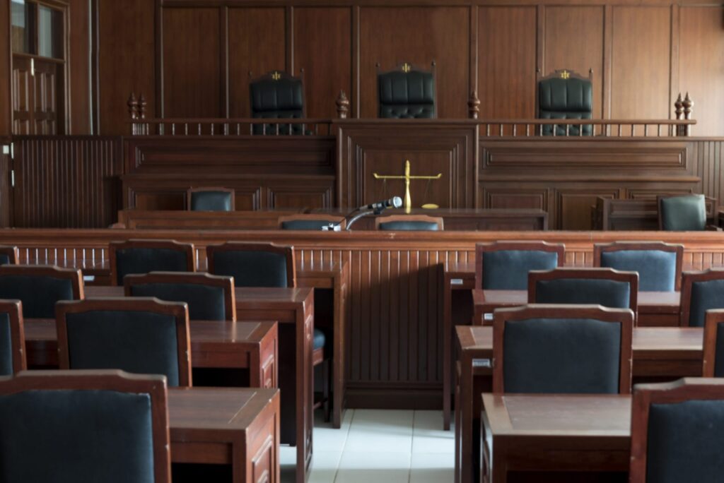 An empty court room with black and brown chairs, representing how one can benefit from calling a Portland criminal defense attorney.